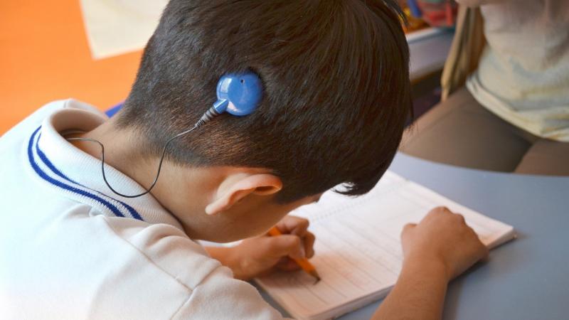 Deaf boy with cochlear implant studying