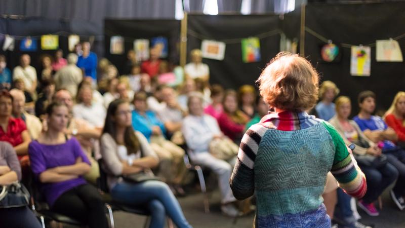 We share our knowledge and latest insights Woman stands in front of an audience.