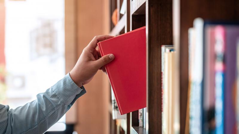 Person takes book of library shelf