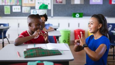 Inclusive education Classroom. Teacher and boy communicatie through sign language